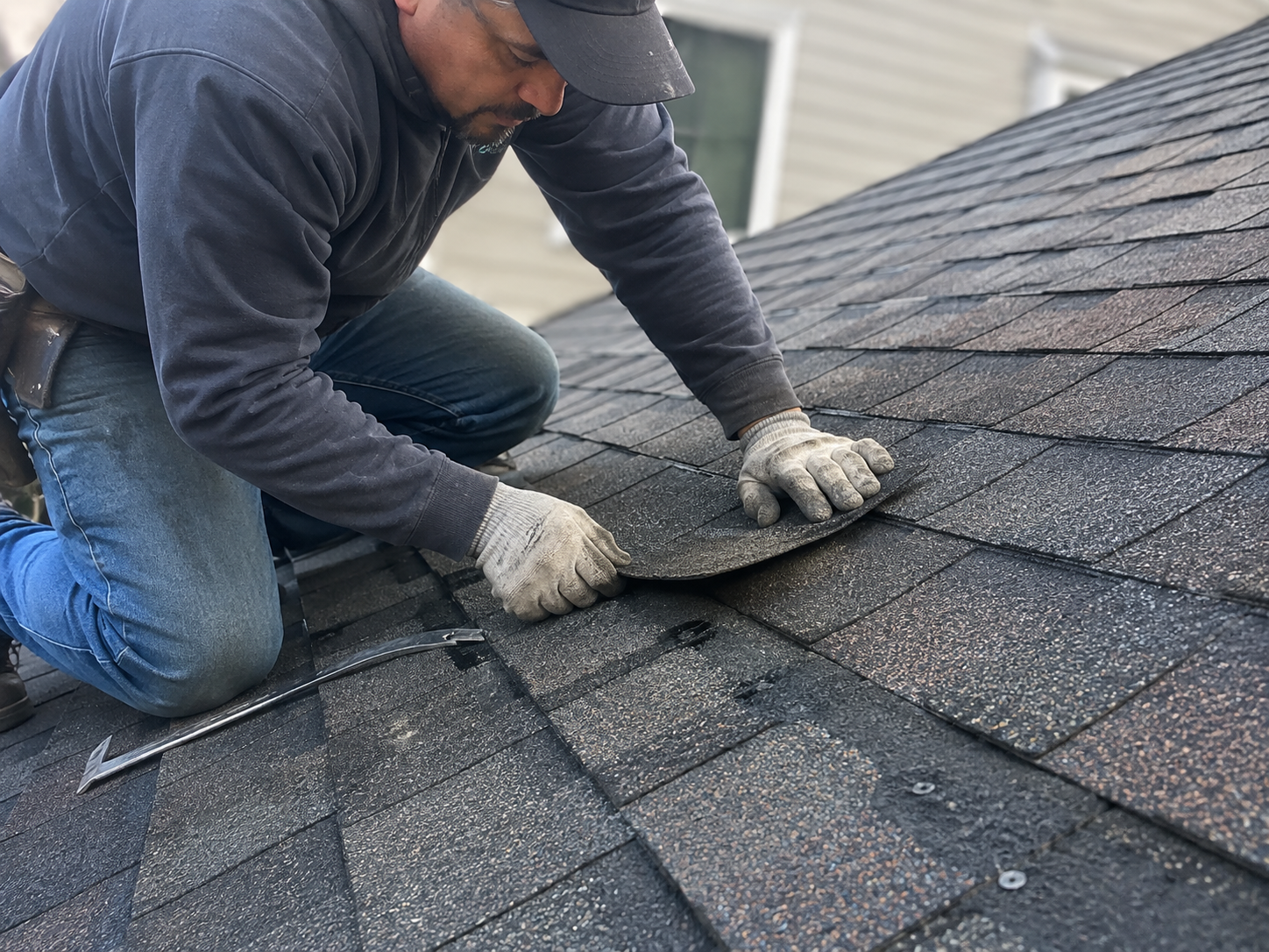 Professional roofer repairing a damaged asphalt shingle